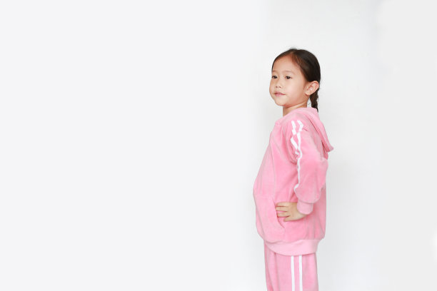 可爱的亚洲小女孩穿着粉红色的运动服或运动服在白色的背景上做运动。图片下载