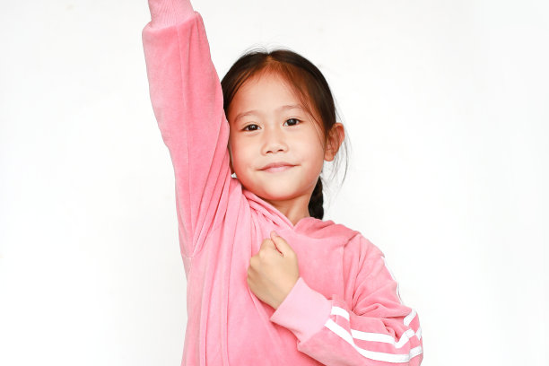 特写亚洲小女孩穿着粉色运动服或运动服，在白色背景上举起双手。赢家运动和成功理念。图片下载