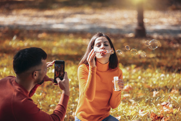 男友在女友吹泡泡时给她拍照。图片下载