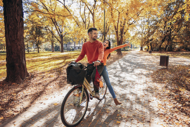 幸福的年轻夫妇在一个阳光明媚的秋日骑着自行车。图片下载