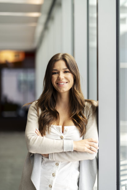 迷人的微笑商人，双臂交叉，长发站在现代办公室图片下载