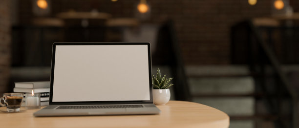远程工作空间模型与笔记本电脑在木制桌面上模糊的黑暗和舒适的咖啡店图片下载