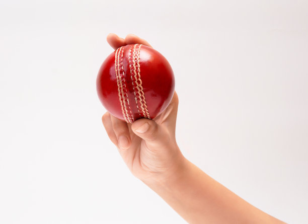 一个女人的手拿着一个红色的测试匹配皮革缝板球特写图片白色背景图片下载