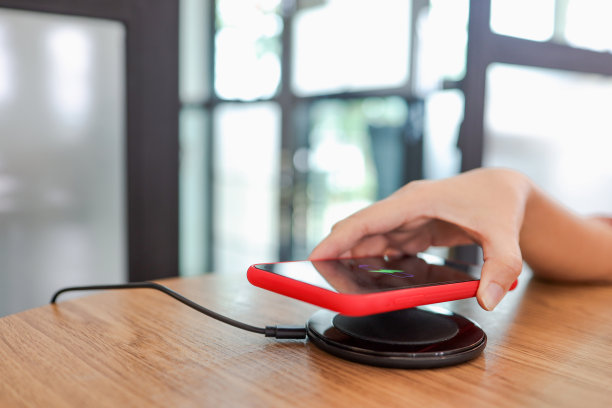 用桌上的无线设备给手机电池充电。智能手机在充电板上充电。手机附近有无线充电器。图片下载