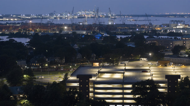 带停车场的城市屋顶:建筑屋顶在夜间有了照明的停车场，变得活跃起来。海运码头在远处，朴茨茅斯，弗吉尼亚州图片下载