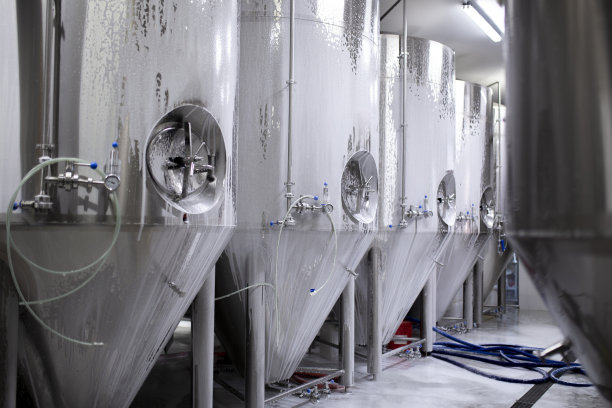 在饮料生产厂的仓库清洗大型金属罐图片下载