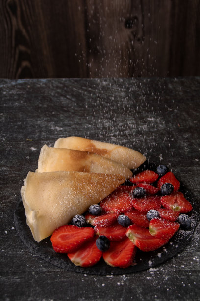 成熟的草莓、蓝莓、煎饼和糖粉的照片。图片下载