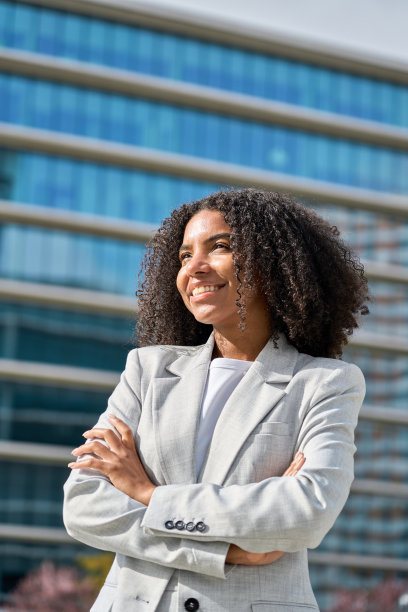 快乐自豪的年轻非裔美国女商人站在城市，垂直。图片下载