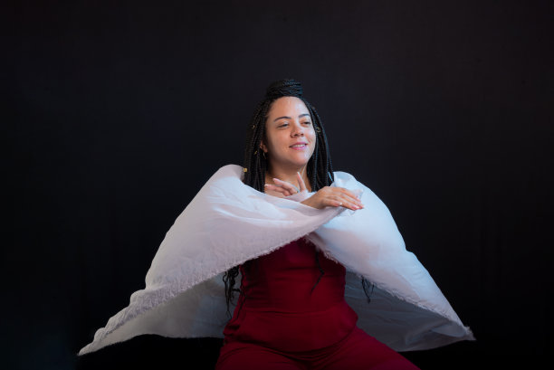 照片中的美女扎着辫子，穿着白布包裹的红色衣服。黑色背景的工作室肖像。图片下载