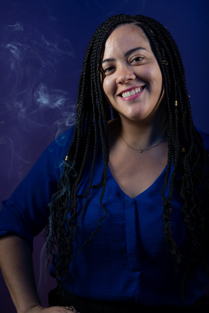 漂亮的女人穿着蓝色的衣服，头发上扎着辫子，微笑着，很开心。孤立的深蓝色背景。图片下载