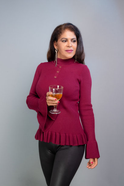 身穿红色衣服的黑发女子端着一杯啤酒。工作室肖像。图片下载