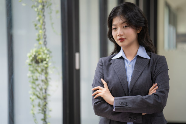 美丽的亚洲女商人站在那里，双臂交叉，望着别处。图片下载