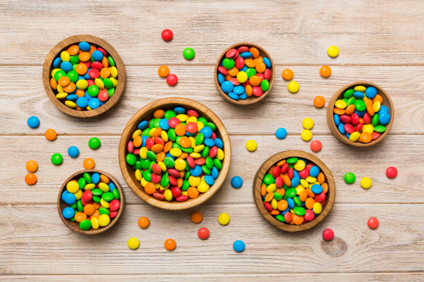 不同颜色的圆形糖果放在碗和罐子里。大品种的糖果和糖果的俯视图与复制空间图片下载