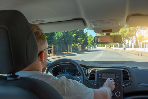 开车的人，司机在方向盘上调节音乐的音量，沿着乡村道路行驶。图片下载