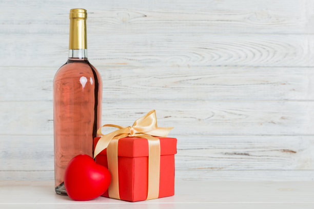 一瓶酒在彩色背景情人节与礼盒。带有当前框透视图的心形，带有复制空间图片下载