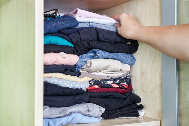 一个女人把洗过和熨过的衣服放在壁橱里。家庭作业。图片下载