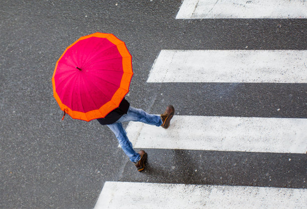 打着红伞的女人在雨中过马路图片下载