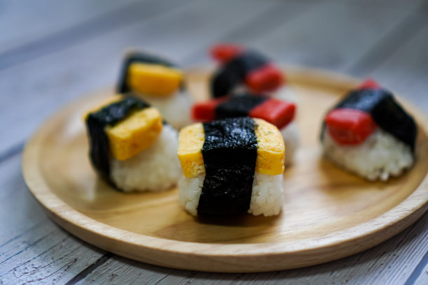 一张特写照片显示，餐桌上的木盘上排列着甜蛋寿司和仿蟹棒寿司。图片下载