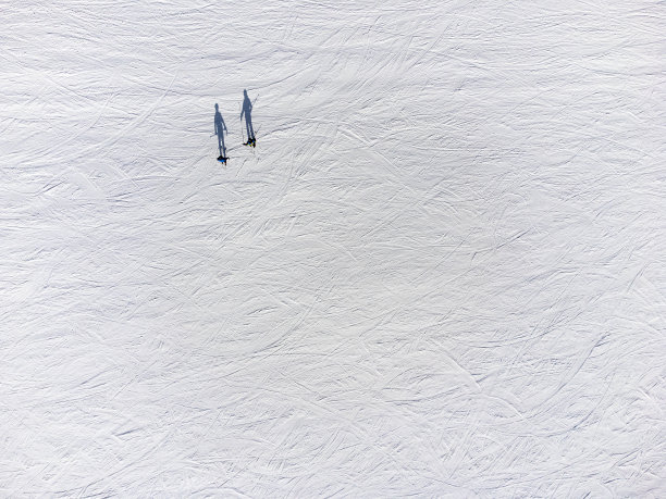 两个滑雪者正上方的雪道上，在不同的阴影位置图片下载