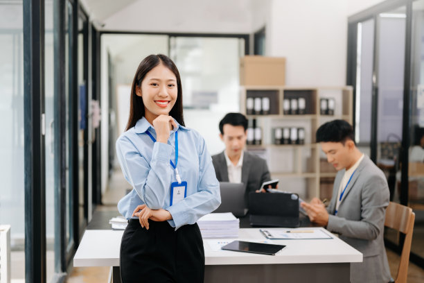 年轻迷人的亚洲女性办公室职员，正西装革履，在办公室对着镜头微笑图片下载