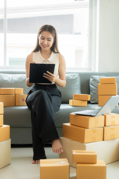 亚洲女商人在沙发上用笔记本电脑检查客户的网上送货箱订单在家里创业中小企业，小企业企业家，自由职业者网上业务的垂直图片图片下载