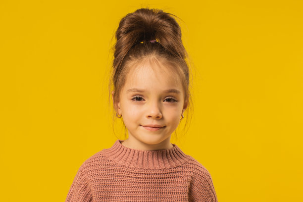 在黄色背景的工作室里，穿毛衣的金发女孩图片下载