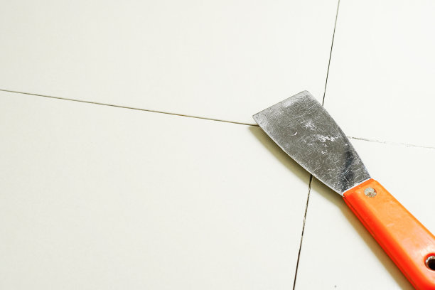 瓷砖灌浆。瓷砖填充瓷砖之间的空间使用不锈钢镘刀。图片下载