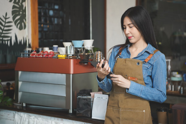 在舒适的咖啡馆里，亚洲咖啡店老板用平板电脑接受顾客的预订。餐厅经理浏览网上订单图片下载