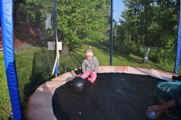 一个小女孩在蹦床上跑来跑去，和她的爷爷一起踢球图片下载