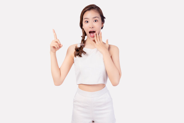 兴奋年轻的亚洲女人指着复制空间看着相机微笑的脸微笑漂亮的女性邀请客户购买你的产品，用于广告与孤立的白色背景图片下载