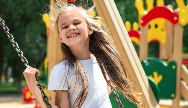 一个快乐的小女孩坐在秋千上微笑着图片下载