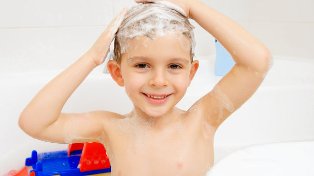 小男孩在家里洗澡时用洗发水洗头的照片。儿童卫生和保健概念图片下载