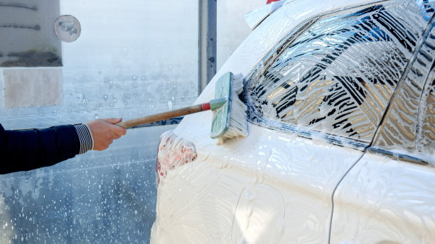 一个男人用肥皂泡沫和刷子清洗他的脏车的特写。汽车护理，运输清洁，脏车。图片下载