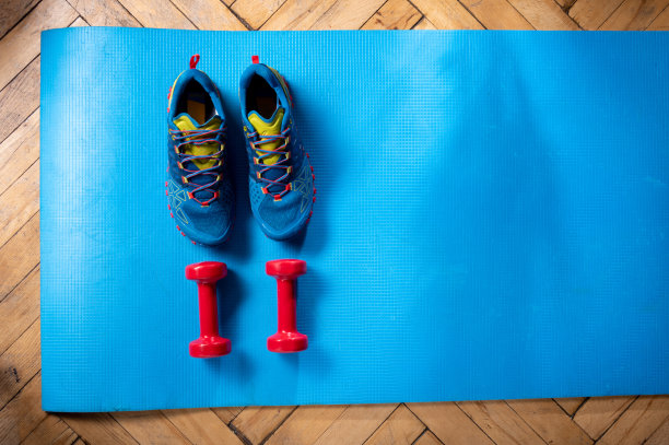 运动跑鞋和健身鞋。健身垫上的健身器材。在家健身。图片下载