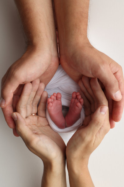 父亲的手掌，母亲的脚都抱着刚出生的婴儿在白色的背景。新生儿的脚放在父母的手掌上。孩子的脚趾、脚后跟和脚的照片图片下载