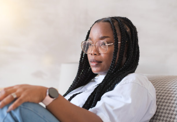 一个年轻的深色皮肤的女人坐在家里的扶手椅上的肖像，心理健康和幸福的概念图片下载