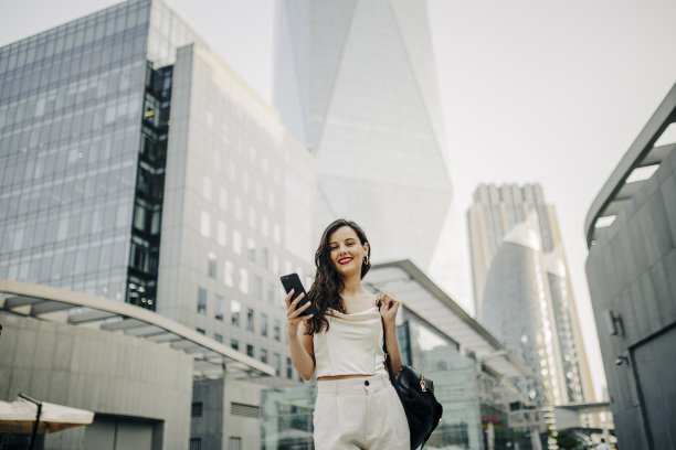一个女人在街上用她的智能手机图片下载