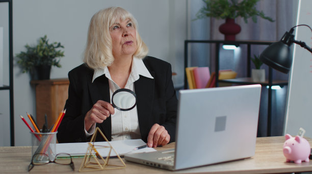 资深女商人通过放大镜观察，调查，分析，阅读文件图片下载
