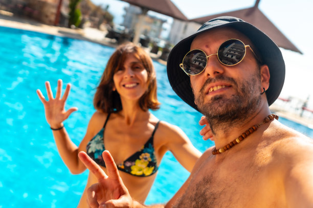 夏天，一对游客夫妇在酒店泳池里自拍，享受假期图片下载