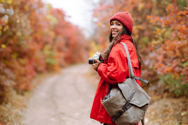 微笑的女游客在秋天的森林里拍照。图片下载