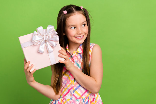 开朗漂亮的女孩穿着时尚的衣服，手臂拿着漂亮的礼品包，在绿色背景上看起来空无一物图片下载