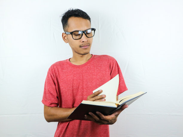 亚洲人拿着书的肖像，表情专注于阅读。图片下载