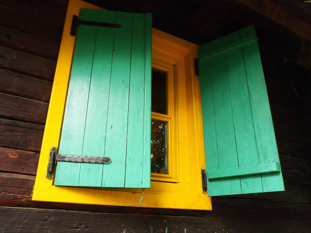 民族木百叶窗上的一扇木框窗户，漆成绿色和黄色。复古的塞尔维亚房子，外观。波斯尼亚和黑塞哥维那，别利纳，Stanisici建筑群。小木屋。图片下载