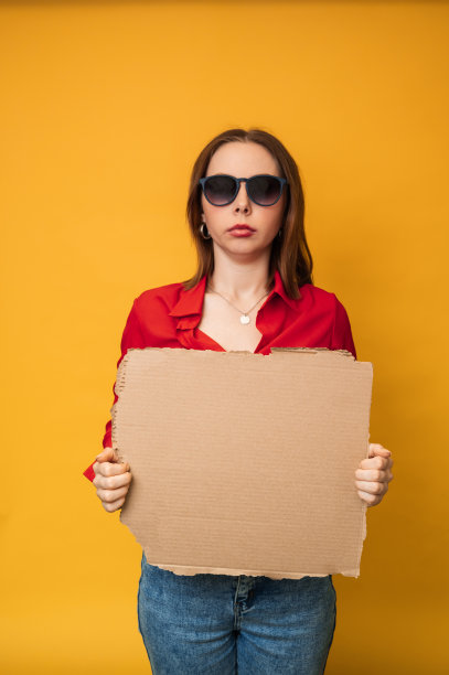 一位美丽、乐观的年轻白人女子正举着一面黄色背景的空横幅。复制空间。图片下载