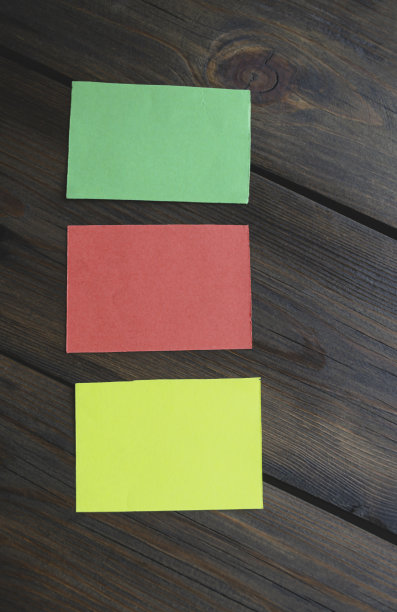 木桌上的三张贴纸。木桌上有红色、黄色和绿色的纸片。桌子上有三张彩色的纸。图片下载
