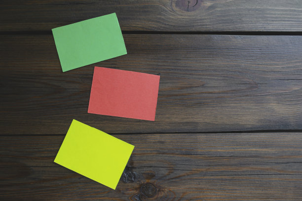 木桌上的三张贴纸。木桌上有红色、黄色和绿色的纸片。桌子上有三张彩色的纸。图片下载