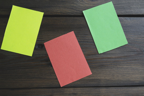 木桌上的三张贴纸。木桌上有红色、黄色和绿色的纸片。桌子上有三张彩色的纸。图片下载