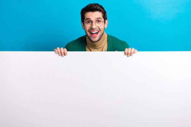 年轻的商人拿着巨大的广告牌的照片惊讶的反应，他的免费服务孤立在海蓝宝石色的背景图片下载