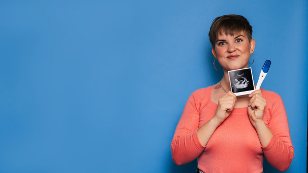 一位孕妇拿着一张婴儿的超声波图像和一张黄色背景的测试，一张母亲手中的超声波图像。复制空间。怀孕和产妇保健的概念。图片下载