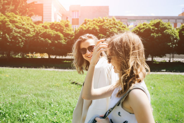 两个时髦的时髦女孩戴着眼镜走在街上。为女性拍摄明亮的夏季照片。美丽的姐妹在户外享受阳光。图片下载